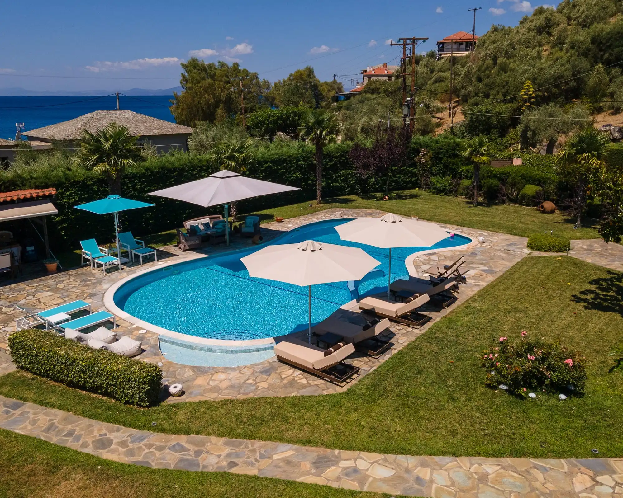 Ομπρέλες Metal Design και ξαπλώστρες γύρω από πισίνα με κήπο στον Αφησσό